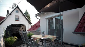 Un patio con una mesa, sillas, una parrilla cubierta y una planta en maceta.
