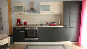 Una cocina moderna con horno empotrado, cafetera y lavabo.