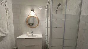 Een badkamer met een wit wastafel, spiegel en douche.