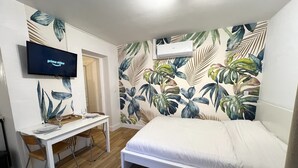 Een slaapkamer met een bed, een bureau en een aan de muur bevestigde televisie.