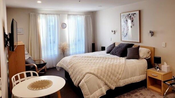 Une chambre d’hôtel comprenant un lit, une table de chevet, une chaise et une petite table avec un set de table.