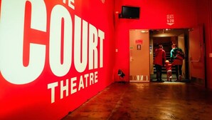 Un mur rouge sur lequel on peut lire : « THE COURT THEATRE ».
