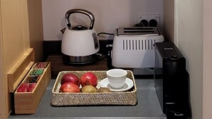 Une petite cuisine équipée d’un four à micro-ondes, d’une bouilloire, d’un grille-pain et d’un plateau de fruits.