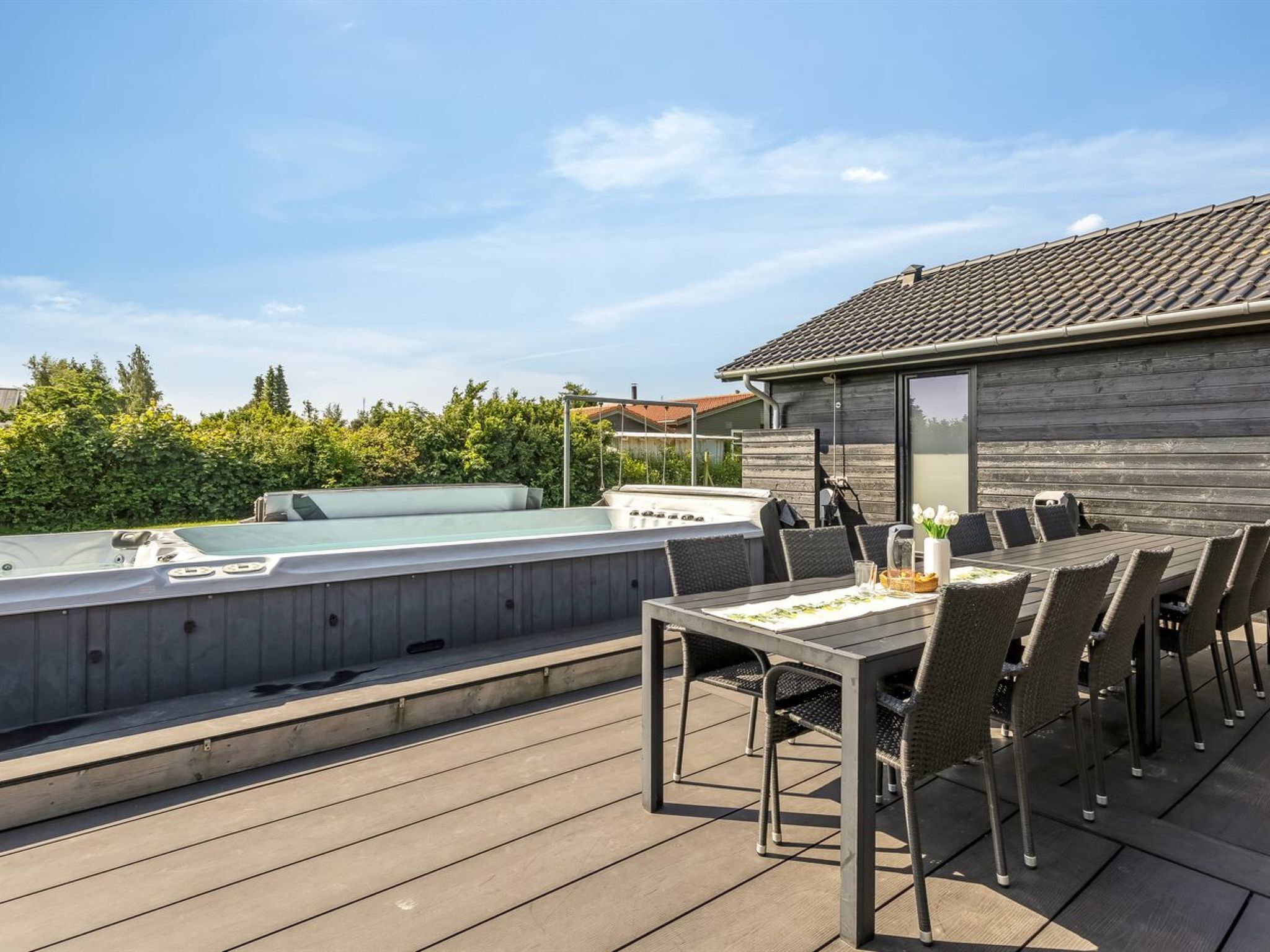 Une terrasse sur le toit avec un jacuzzi, une table à manger et des chaises, et une vue sur les environs.