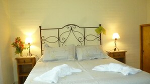 A double bed with a metal headboard, two bedside tables with lamps, and a wooden door. - Casa de Piedra (Mina Clavero)