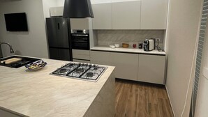 Une cuisine moderne dotée d’un îlot central, d’appareils électroménagers intégrés et d’un luminaire suspendu.