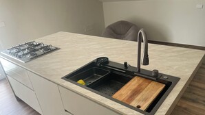 Une cuisine équipée d’un évier encastré, d’une cuisinière à gaz et d’une planche à découper en bois.