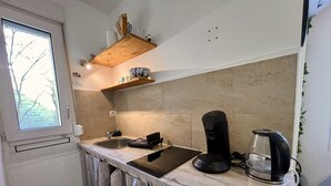 A compact kitchen with a window, a sink, a stove, and a coffee maker. - Quiet & Stylish Home With Garden (Le Mans)
