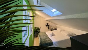 A modern hotel room with a skylight, a bed with white linens, a bedside table, and a potted plant. - Quiet & Stylish Home With Garden (Le Mans)