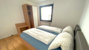 A bedroom with a bed, a wooden wardrobe, and a window. - Apartment in Adenau (Adenau)
