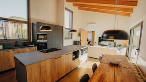Una cocina moderna con armarios de madera, una isla central y un comedor con mesa y sillas de madera.