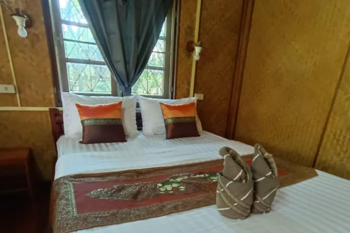A wooden-framed room with a bed, a window with curtains, and a wall-mounted light fixture.