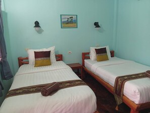 Two single beds with wooden frames and white bedding, a small bedside table, and a wall-mounted picture. - MG Guest House (Thani)