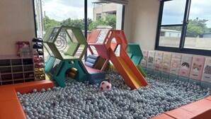 Un espace de jeux avec une piscine à balles, des toboggans et un ballon de foot.