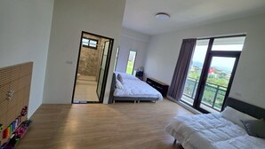 Une chambre spacieuse avec deux lits, un plancher en bois, une grande fenêtre et une vue sur l’extérieur.