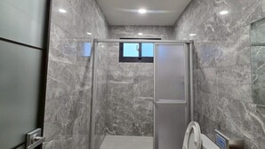 Une salle de bain moderne avec une douche à l’italienne, des toilettes et un lavabo.
