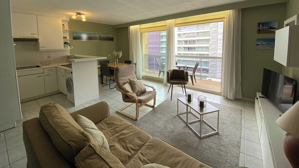 A compact living space with a kitchenette, a dining area, a sofa, and a balcony with a view of the city. - Apartment in Nieuwpoort Near the Beach (Nieuwpoort)