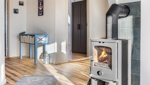 A modern living room with a wood-burning stove, a blue chair, and a small table with baskets.