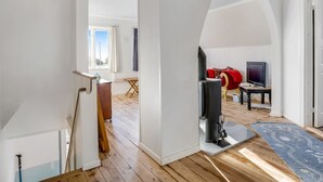 A spacious living area with a wooden floor, a fireplace, a television, and a red sofa.
