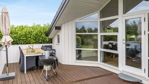 A covered patio area with a table and chairs, a grill, and a large sliding glass door leading to a garden. - "Naimi" - 30km from the sea by Interhome (Toftlund)