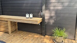 A wooden bench with two white speakers, a potted plant, and a dark wooden wall. - "Konrad" - 300m from the sea by Interhome (Hals)