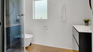 A modern bathroom with a toilet, a small window, a towel hanging on the wall, and a potted plant on the counter. - "Konrad" - 300m from the sea by Interhome (Hals)