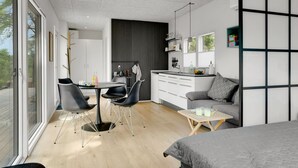 A modern, compact living space with a dining area, kitchenette, and a large window providing natural light. - "Konrad" - 300m from the sea by Interhome (Hals)