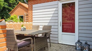 A patio with a table and chairs, a door with a red glass panel, and two lanterns.