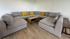A modern living room with a grey sectional sofa, a wooden coffee table, and a hanging light fixture. - Cottage in Saint-vincent Near Le Mans (Saint-Vincent-du-Lorouër)