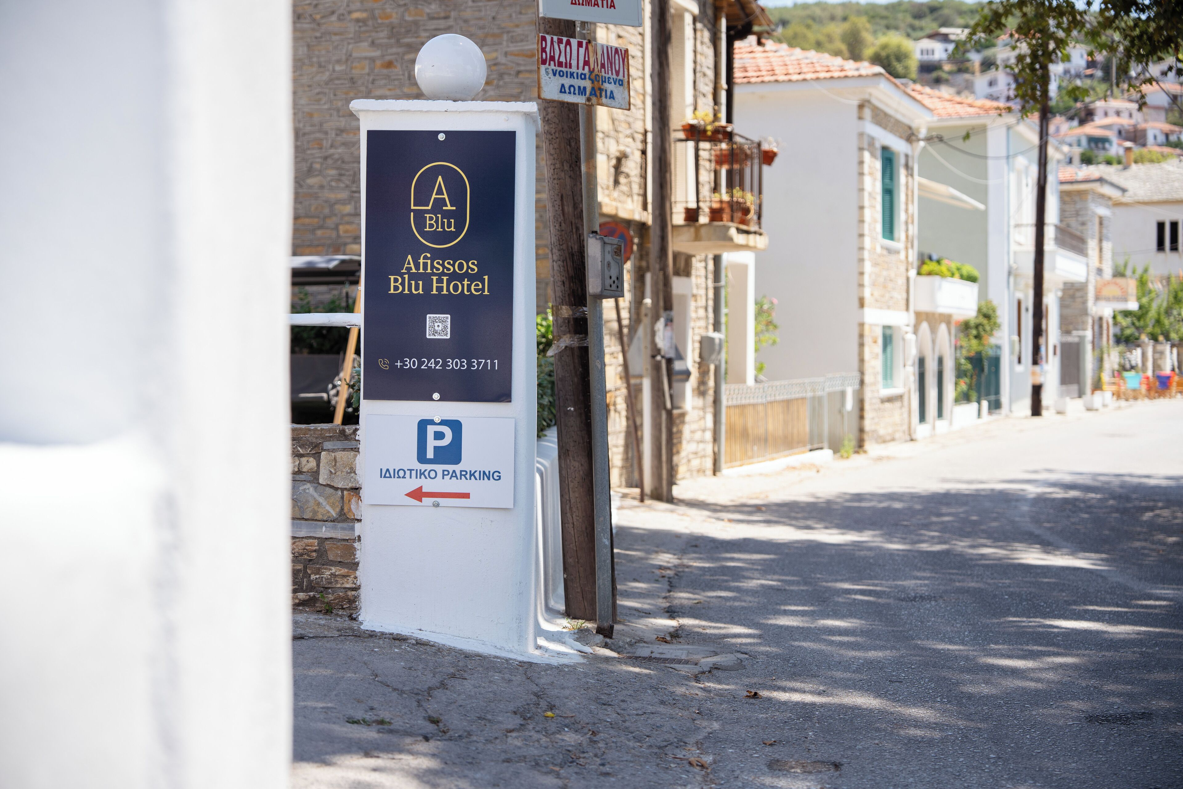 Een bordje voor Afissos Blu Hotel met een parkeerrichtingswijzer.