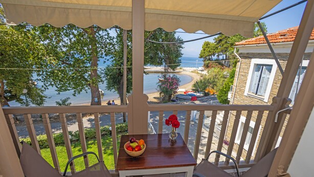 Ein Balkon mit Tisch, Stühlen, einer Obstschale und einem Blumenstrauß.