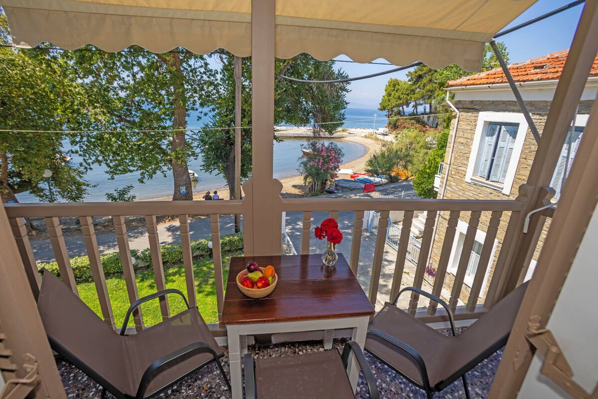 Ein Balkon mit Tisch, Stühlen, einer Obstschale und einem Blumenstrauß.