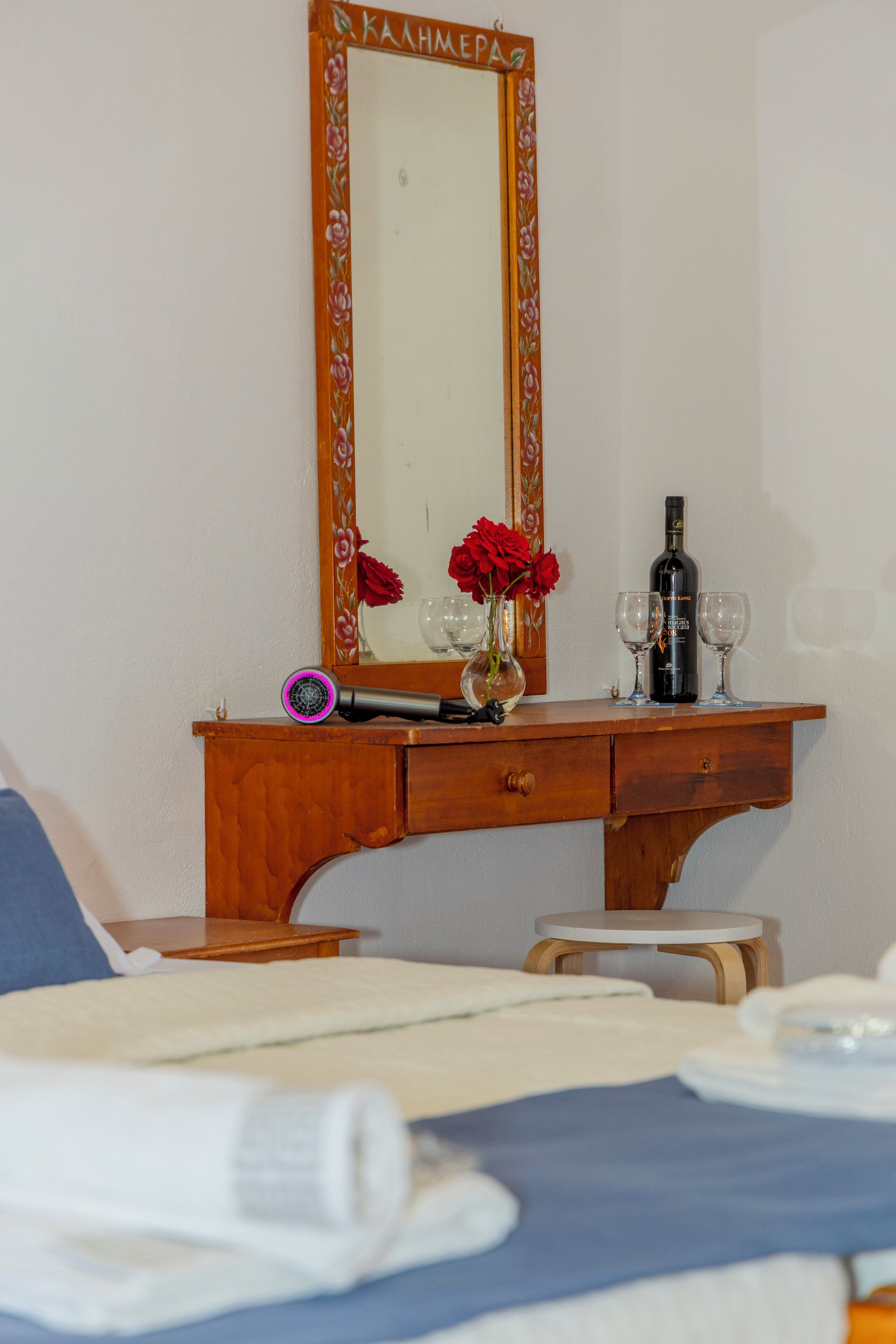 A wooden dresser with a mirror, a bottle of wine, and two glasses.