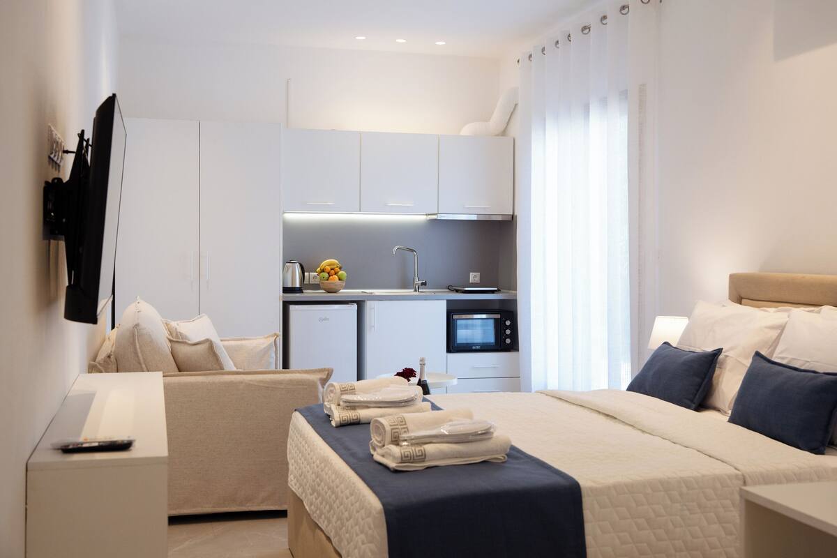 Ein modernes Hotelzimmer mit Bett, einer Couch, einem Schreibtisch und einer Küchenzeile.