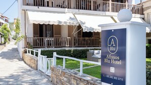 Ein Hotel mit zwei Etagen, einem Balkon, einem Schild für das Afissos Blu Hotel und einem Parkplatzschild.