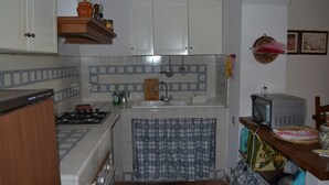 A compact kitchen with white cabinets, a gas stove, a sink, and a microwave.
