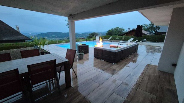 An outdoor patio with a pool, seating area, and a fire pit. - Villa near Annecy with swimming pool (Fillière)