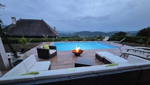 A swimming pool with a fire pit and outdoor seating. - Villa near Annecy with swimming pool (Fillière)