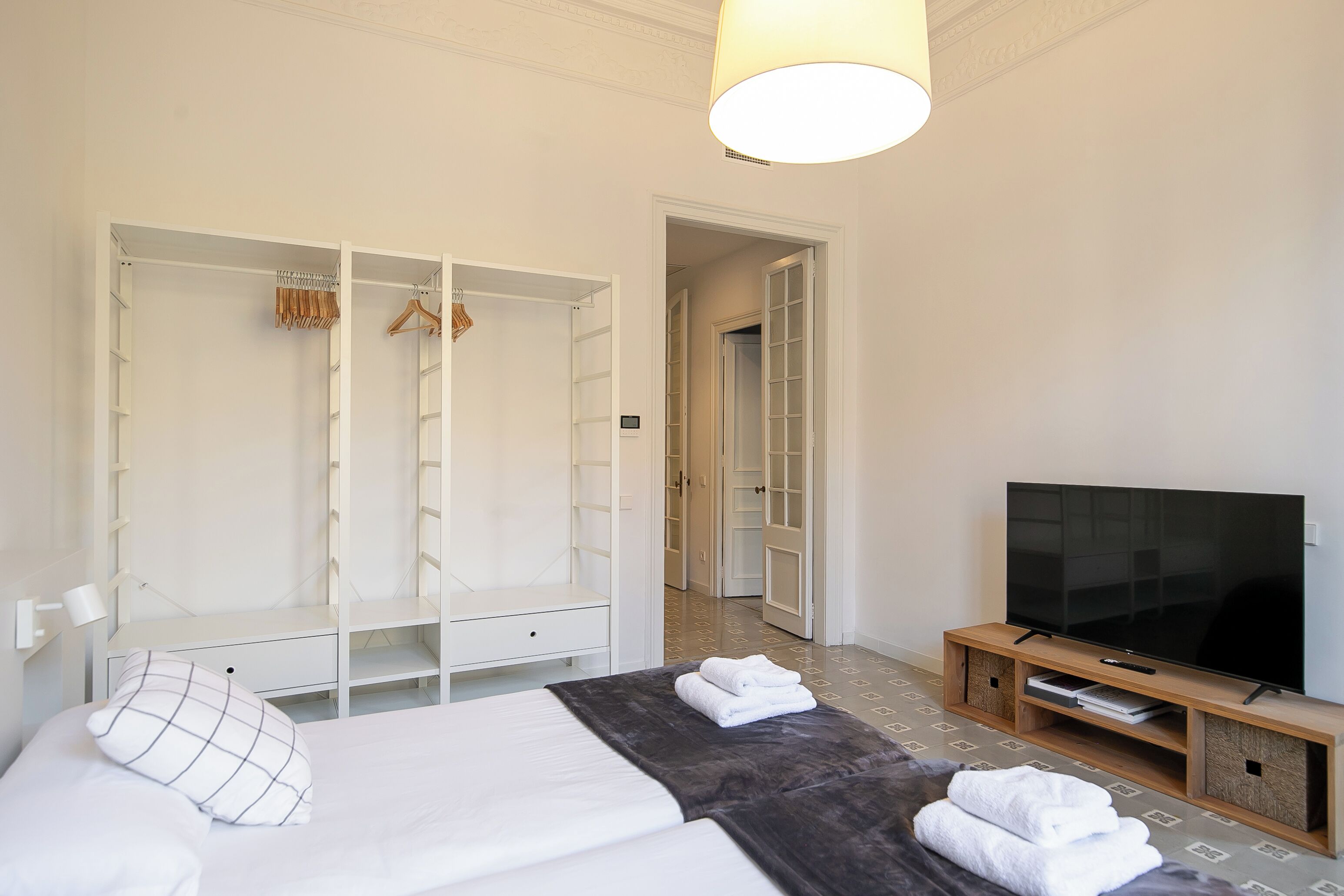 A hotel room with a bed, a TV, a wardrobe, and a walk-in closet.