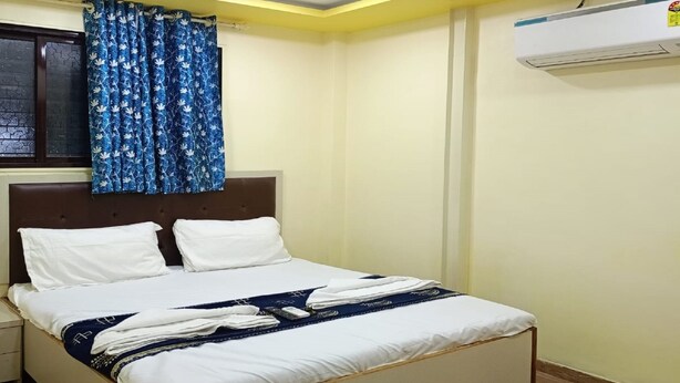 Una cama bien hecha con ropa de cama blanca y azul, un ventilador de techo y un equipo de aire acondicionado en la pared.