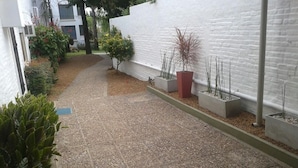 A narrow pathway with gravel, bordered by white walls and various potted plants. - Hotel Palmar (Colon)