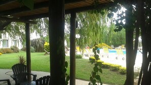 A covered outdoor area with chairs and a pool in the background. - Hotel Palmar (Colon)