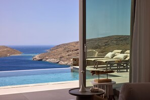 A modern room with a large sliding glass door leading to a private pool overlooking a scenic coastline. - Orias Luxury Suites Kythnos (Kithnos)