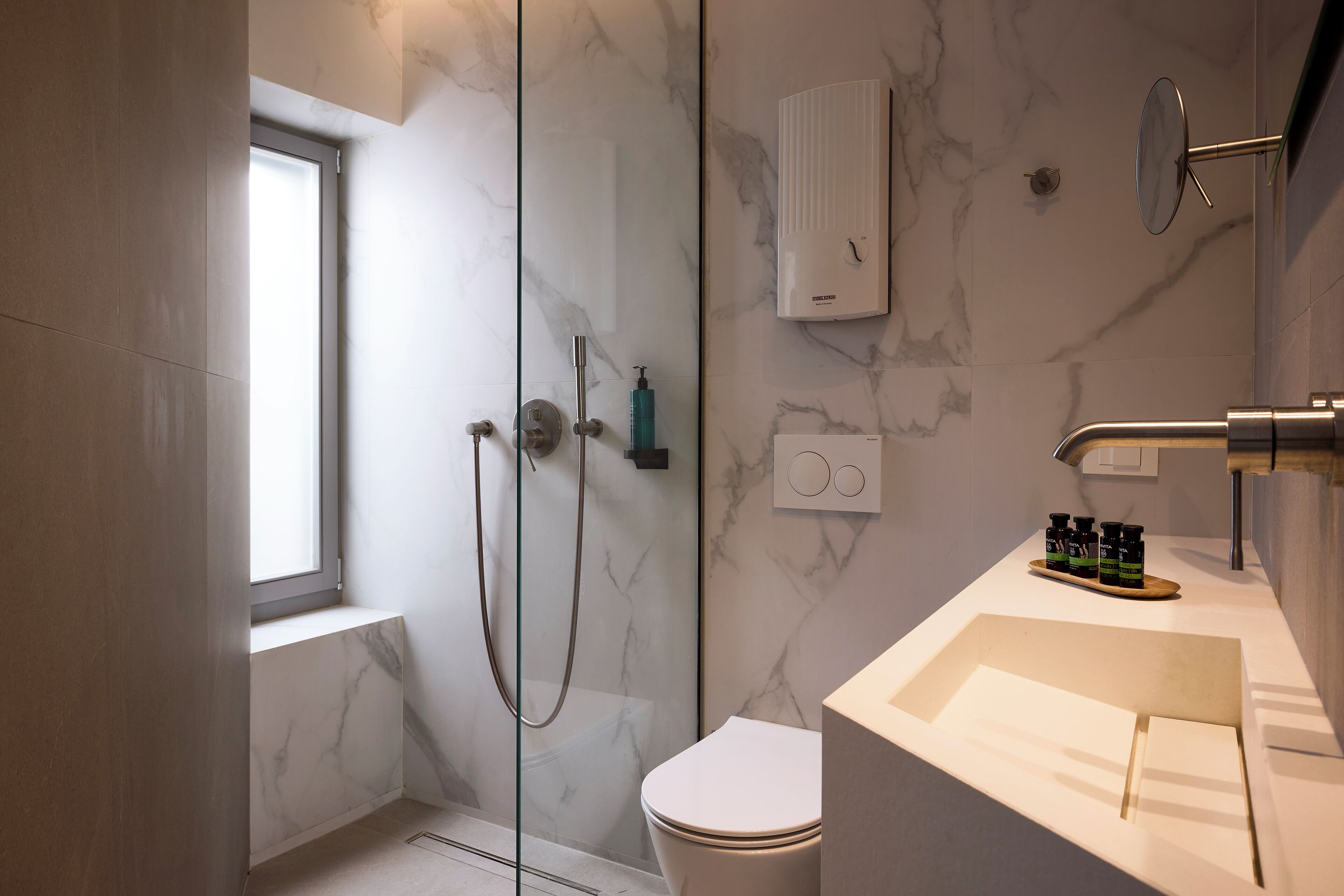 A modern bathroom with a glass-enclosed shower, a toilet, and a sink with toiletries.