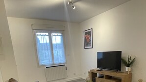 Un salon moderne avec un canapé en cuir marron, un téléviseur à écran plat posé sur un meuble en bois et une petite table sur laquelle se trouve une plante.