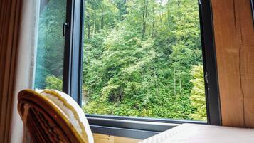 A room with a large window overlooking a dense forest.