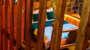 A wooden-framed room with a bed, a stone wall, and a sign indicating a heart symbol.