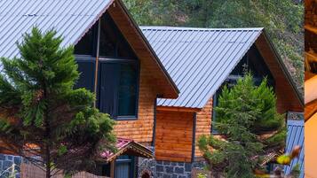 A cabin with a sloped roof, wooden exterior walls, and a stone foundation.