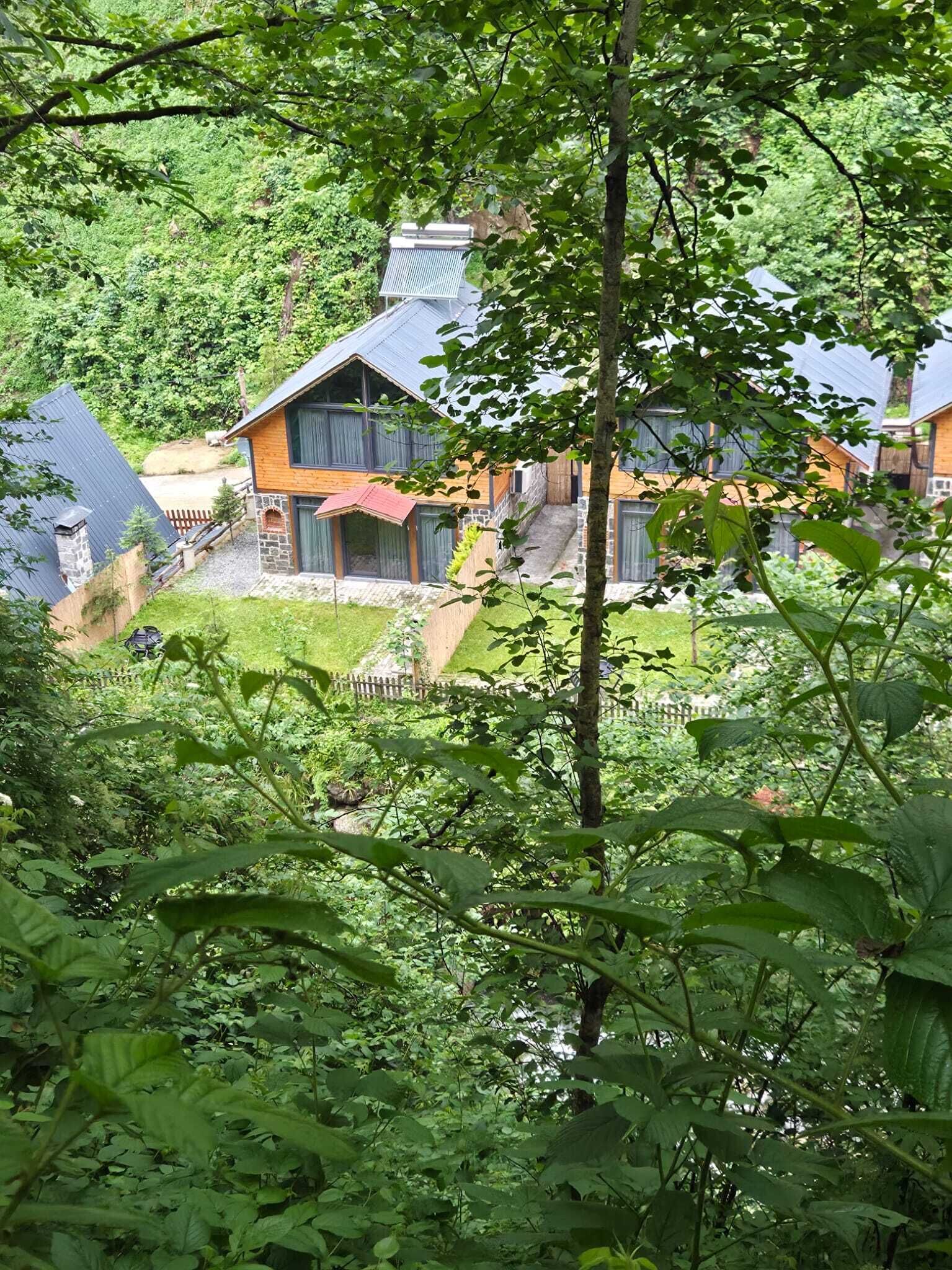 Una casa moderna con fachada de piedra, ventanas amplias y una terraza de madera.