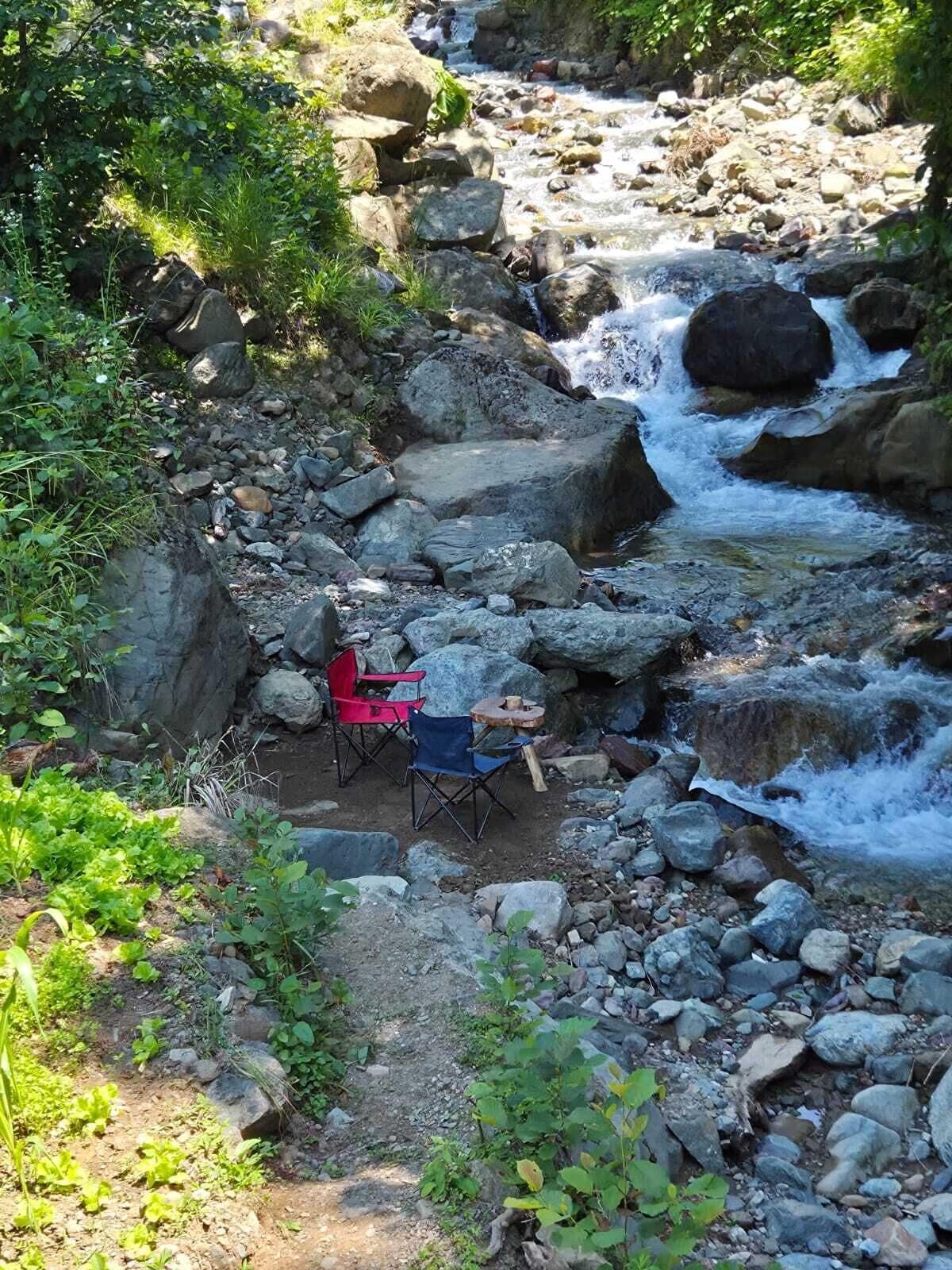 Un arroyo pedregoso con una silla y una mesa dispuestas para un picnic.